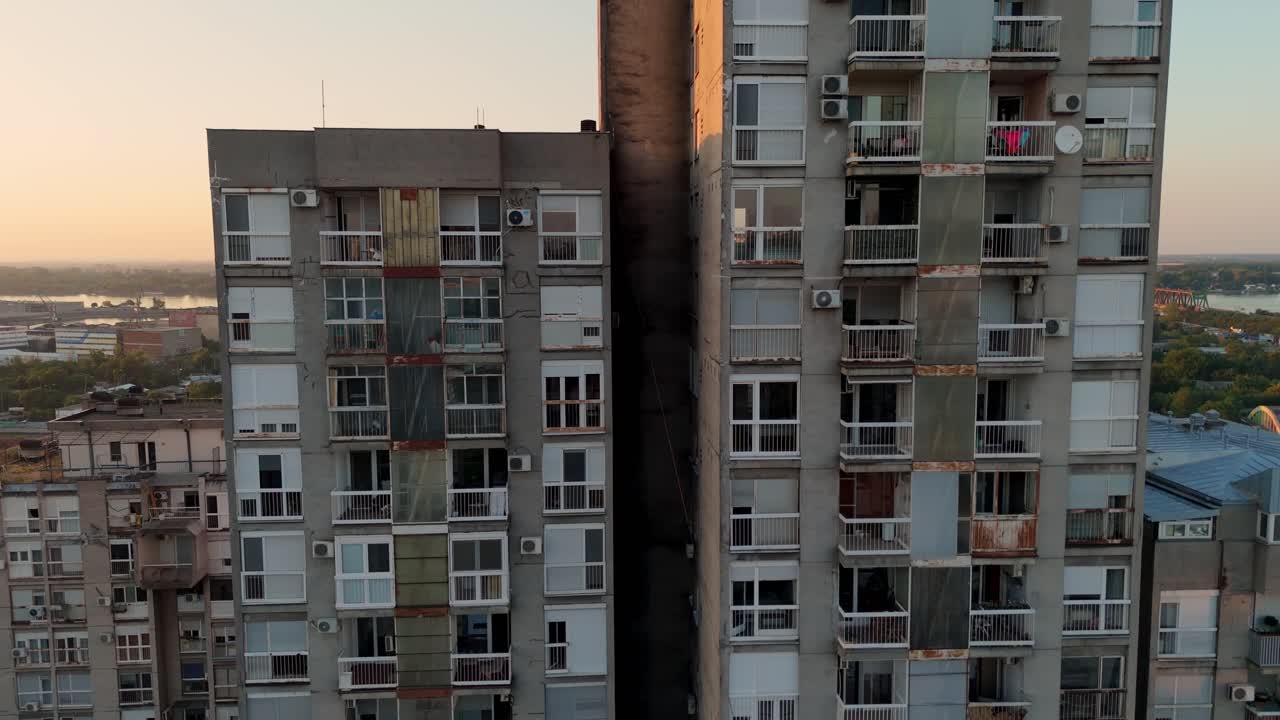 Aerial view of Belgrade brutalist residential buildings at sunset, drone close up showing raw concrete architecture, warm evening light, in modern Serbia