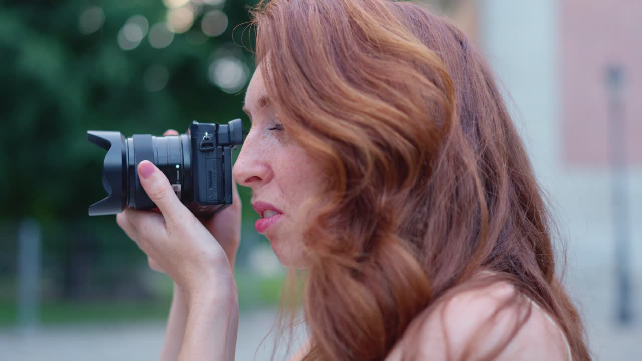 Woman with red hair taking photos outdoors with a camera