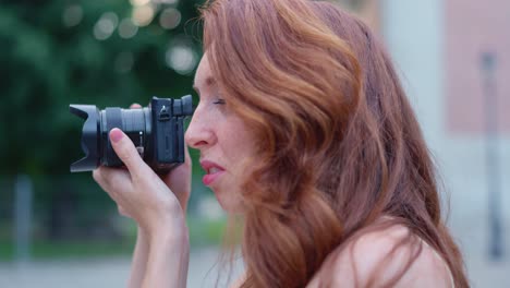 woman with red hair taking photos outdoors with a camera