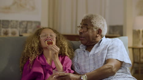 linda niña y abuelo comiendo juntos un refrigerio nocturno
