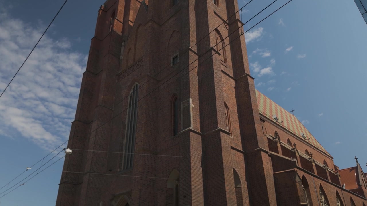 La Cattedrale di Santa Maria Maddalena a Breslavia, Polonia, mostra l'architettura gotica con la sua imponente facciata e dettagli intricati sotto un cielo blu vibrante. Ripresa in picchiata.