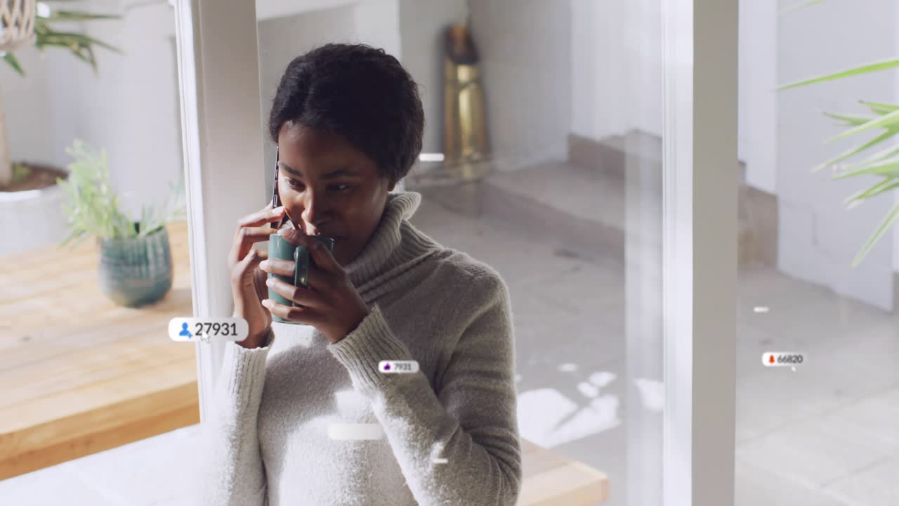 Woman taking call near glass, holding mug, notifications multiplying around her for technology