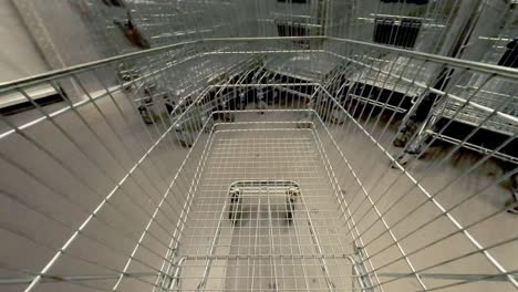 pov shot: un cliente conduciendo un carrito vacío dentro del pasillo de un supermercado, poniéndolo de nuevo en la fila de los usados