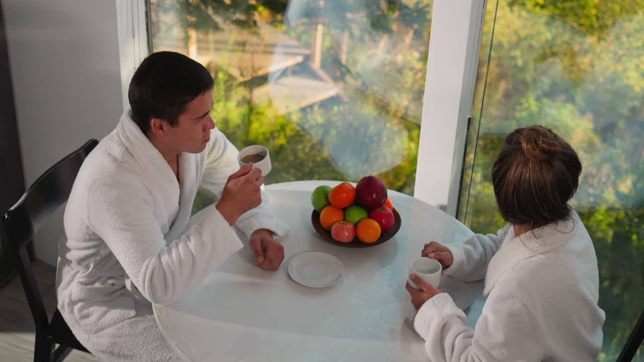 남자와 여자가 아침 식탁에서 대화합니다. 형제와 자매는 가족 휴가에서 함께 아침 식사를합니다. 가족 구성원들과 함께 휴식을 취합니다.