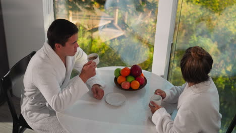 man talks to woman at table in morning. brother and sister have breakfast time together on family vacation. relaxing vacation with family members