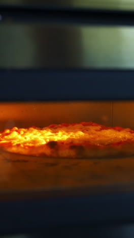 delicious pizza in hot oven. chef is taking ready bakery with a special pizza spatula. process of baking pizza in pizzeria. vertical video