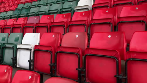 empty stadium with red green and which spectator seats in the sports stand