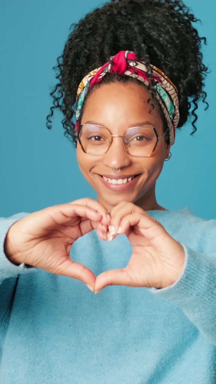 Giovane donna che sorride e forma un cuore con le mani