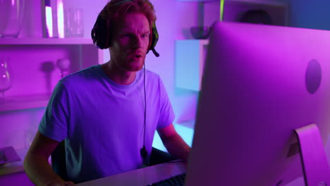 esport profesional jugando en casa con luces de neón en primer plano. hombre rojo frustrado