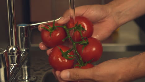 hands washing tomatoes under water tap