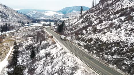 Semi-Truck-Traveling-on-Yellowhead-Highway-5-in-the-Snowy-Thompson-River-Valley-Near-Kamloops,-Amidst-a-Breath-Taking-Landscape-of-Snow-Covered-Mountains