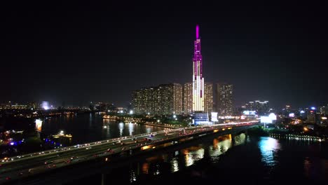 muñeca aérea a la izquierda del tráfico conduciendo por un puente en una ciudad moderna como ho chi minh por la noche