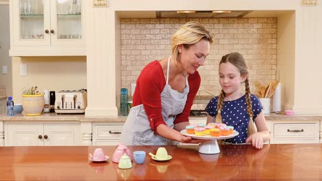 Smiling-mother-and-daughter-discussing-over-cupcakes-4K-4k