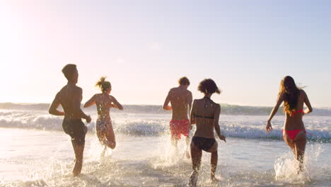 friends running in the ocean waves