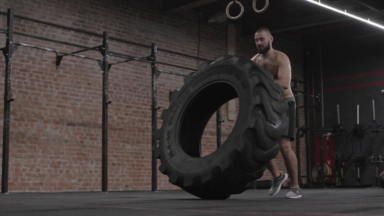 Caucasian Sportsman Flipping Tire in Gym
