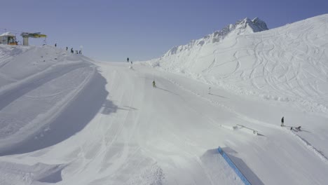 Flyover-of-Nordkette-ski-resort-above-Innsbruck,-Skyline-terrain-park-reveal-into-Austrian-Alps-peak-ski-resort