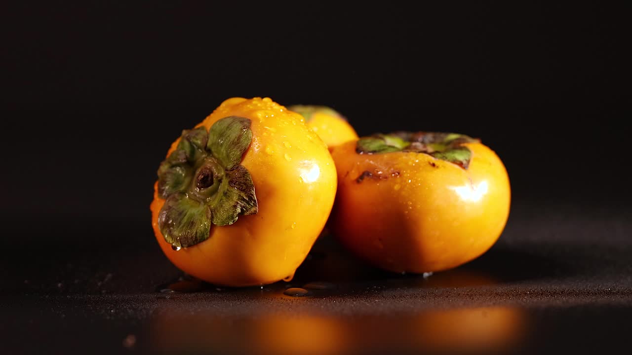 primer plano de persimiones en una superficie oscura