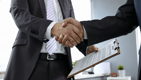 business partners handshake with each other symbolizing teamwork cooperation. two male professionals shaking hands after sealing deal in large office building. concept of partnership among colleagues