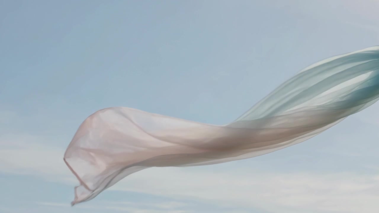 Sciarpa traslucida color pastello che fluttua in un cielo azzurro limpido, con una brezza leggera che ne solleva le pieghe.