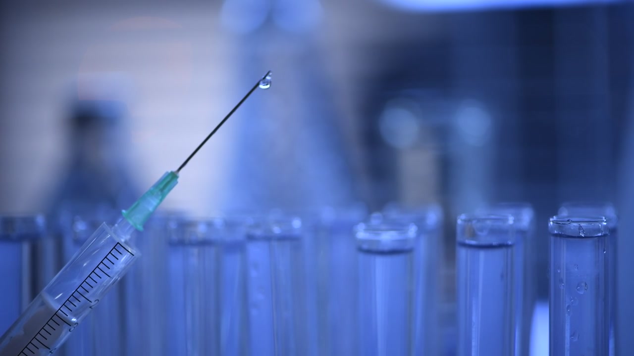 Siringa che espelle gocce di liquido in un laboratorio medico