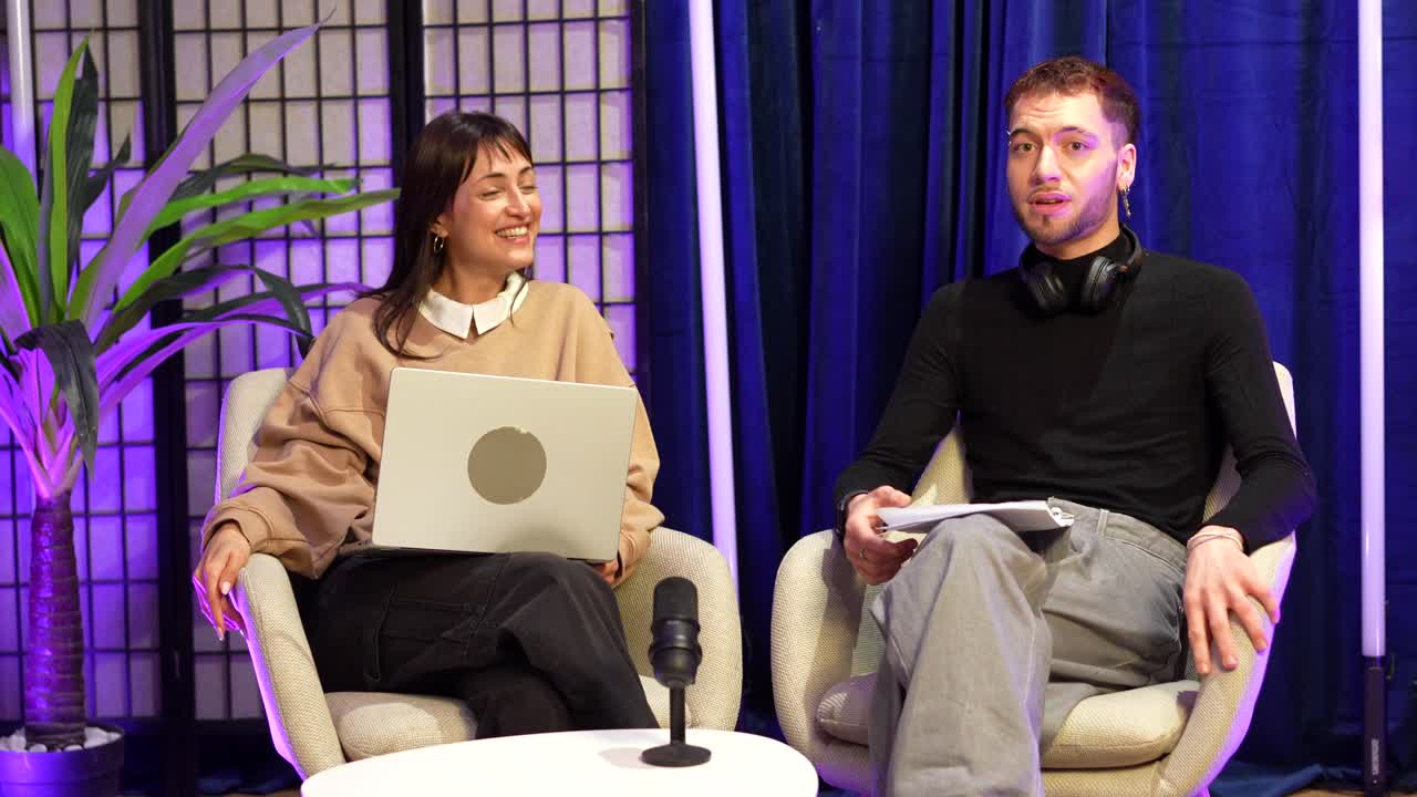Mand og kvinde er værter for en podcast eller et interview i et moderne studie