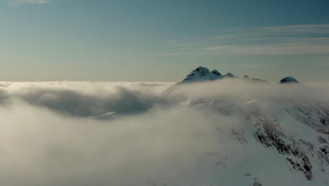aerial shot in the clouds above snow-capped mountain peaks