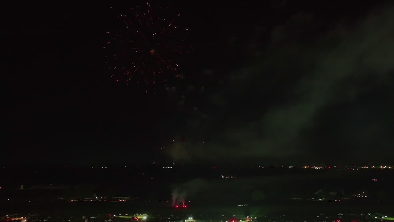 Fireworks burst in dazzling colors over a bustling city during a nighttime celebration. Bright lights and patterns create a festive atmosphere that captivates viewers.