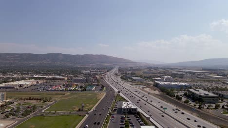 Vista-Aérea-Sobre-El-Tráfico-De-La-Autopista-Con-Las-Montañas-De-Utah-En-Segundo-Plano