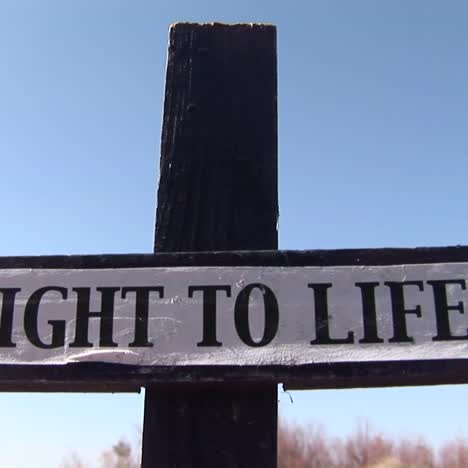 a wooden cross has a right to life banner attached