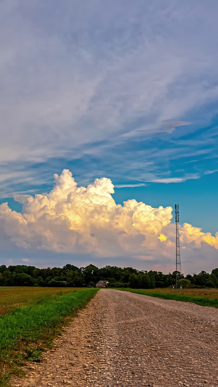 Layers of cumulus clouds moving along bursting in sky looking scenic over a countryside field