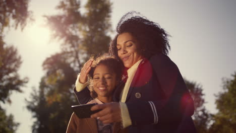 Happy-mother-kid-making-selfie-together-in-warm-golden-sunlight-spring-park.