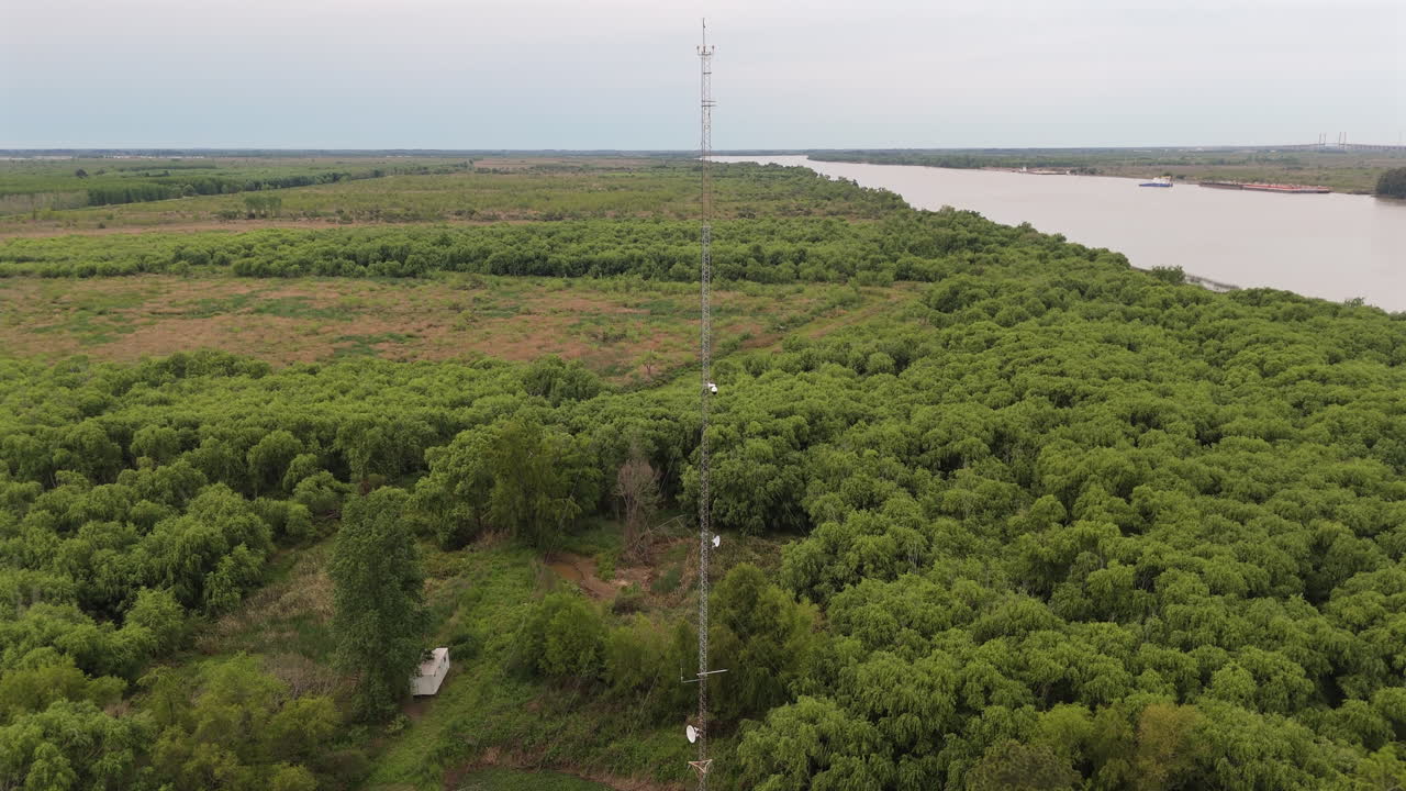 Weather monitoring tower in a remote wetland forest area by a winding river.