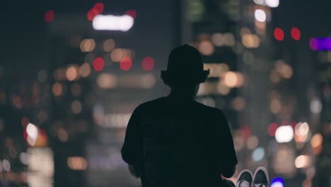 Young-adult-sitting-on-ledge-of-skyscraper-uses-his-phone-to-record-downtown-Los-Angeles-1