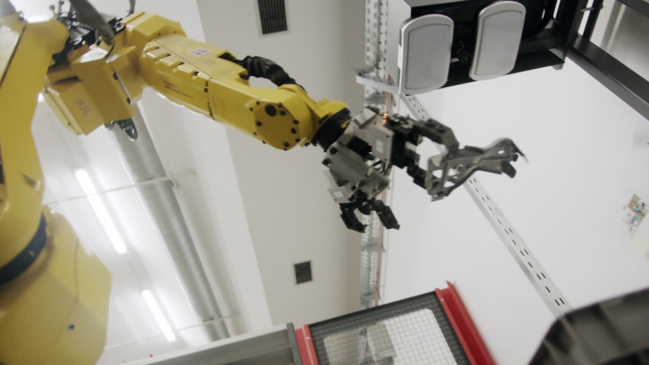 Yello robot arm moving metallic parts during a production process