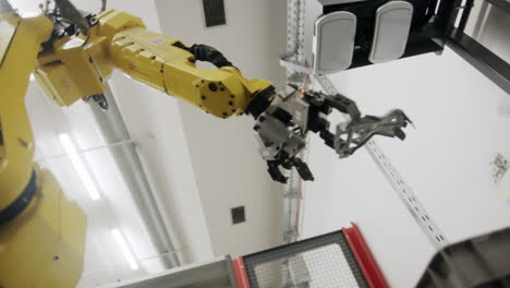 yello robot arm moving metallic parts during a production process