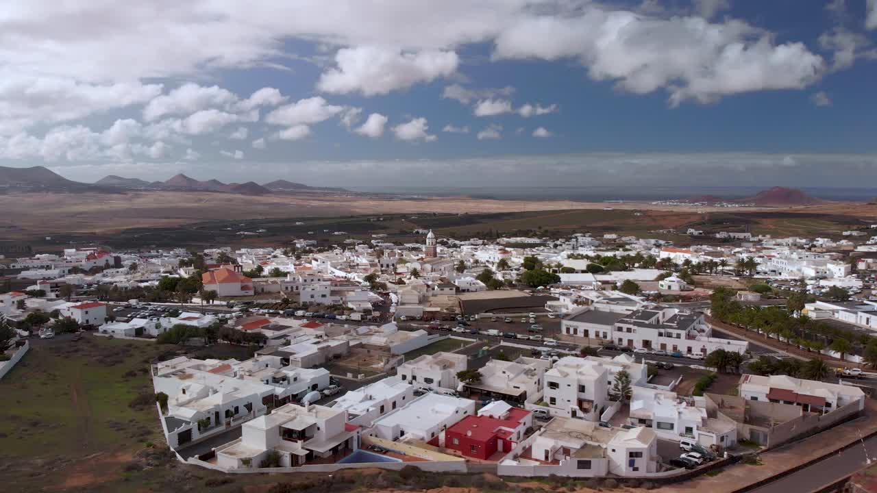 화산 지형 위의 하얗게 씻겨진 마을을 향해 날아갑니다