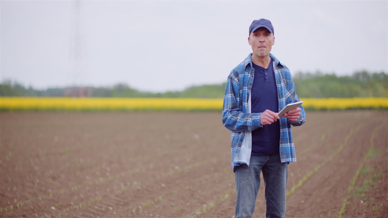 Landwirt erklärt und benutzt ein digitales Tablet auf dem landwirtschaftlichen Feld