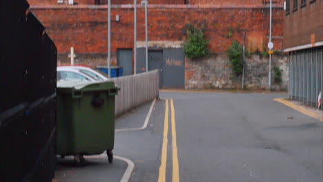 Un-Hombre-Sentado-En-El-Alféizar-De-Una-Ventana-En-Un-Bloque-De-Construcción-De-Ladrillo-Rojo-En-Belfast,-Irlanda-Del-Norte