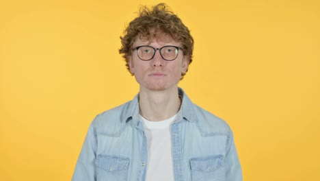 joven pelirrojo serio, fondo amarillo