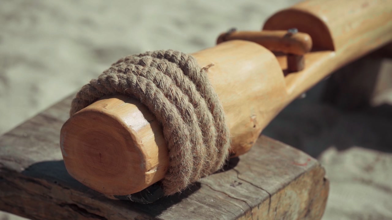 Gros plan sur une corde épaisse enroulée autour d'une poutre en bois sur la plage