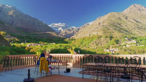 tourist eating breakfast at the rooftop terrace in imlil with toubkal view, morocco