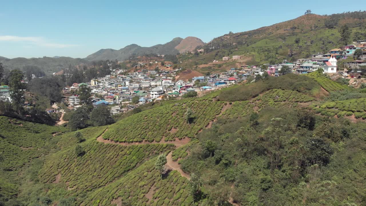 인도 문나르에 있는 차 정원으로 둘러싸인 언덕의 경사면에 정착한 시골 마을 - 공중 와이드 설정 샷