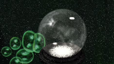 animation of christmas snow globe and green bubbles with snow falling