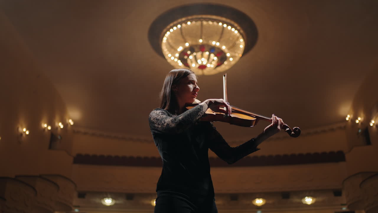 una violinista profesional está tocando el violín en la escena de la ópera retrato de un solista en la sala filarmónica