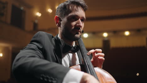 handsome man is playing cello on scene of old opera house closeup portrait of cellist in philharmonic hall