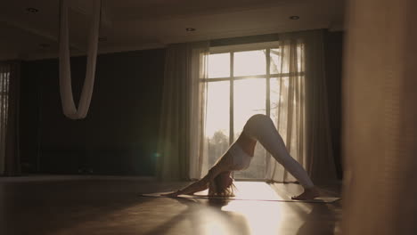 a young woman in white sportswear is stretching with a large hall with large windows in a slow-motion scheme the sun's rays shine through the window. healthy lifestyle healthy morning