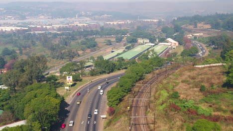 drone shot of train tracks next to a busy road in south africa 4k