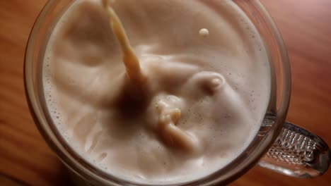 tabletop slom motion shot of milk and sugar pourred into a cup of coffee