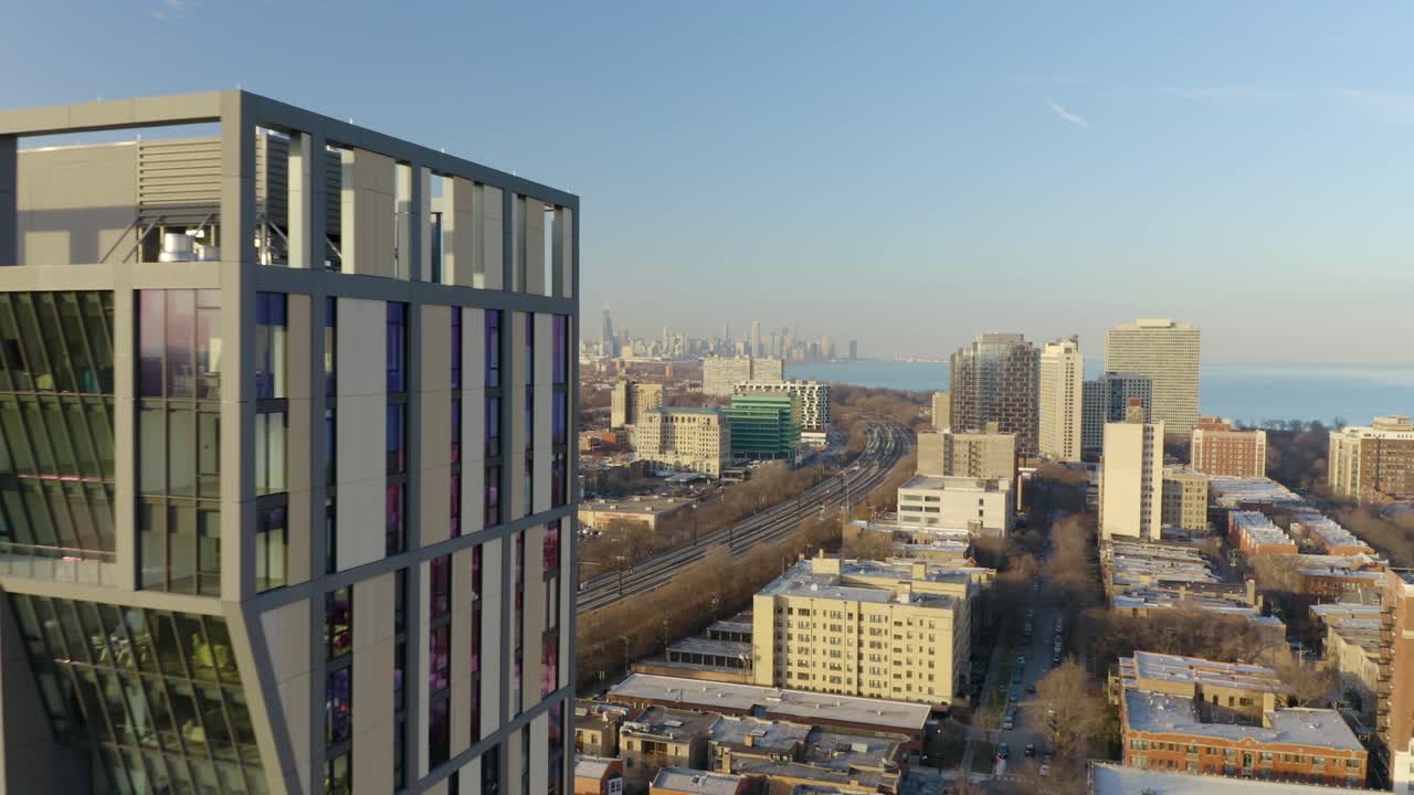 Drone voa por um prédio moderno, revelando o horizonte de Chicago à distância.