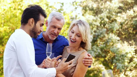 Man-showing-mobile-phone-to-couple-in-balcony